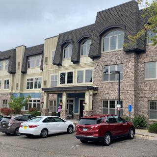 A view of a multi-story building with parked cars in front.
