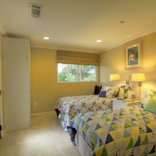 A cozy bedroom with twin beds, warm lighting, and a window view.