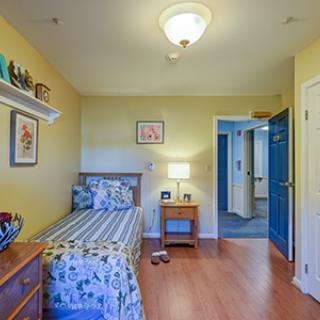 A cozy bedroom with a single bed and a nightstand with a lamp.
