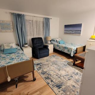 A cozy bedroom featuring two beds with blue accent decor, complemented by a comfortable chair and a stylish rug.