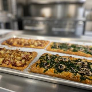 A tray of freshly baked flatbread pizzas with various toppings in a kitchen setting.