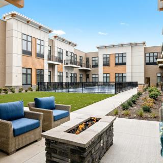 A modern apartment complex featuring a landscaped courtyard with outdoor seating and a fire pit.