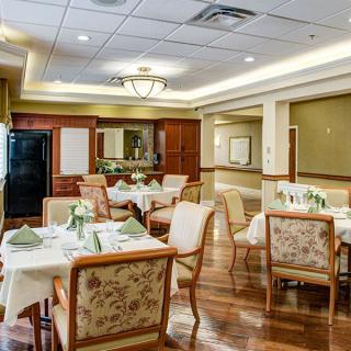 A elegantly set dining area with multiple tables and chairs, featuring warm lighting and tasteful decor.