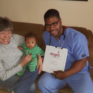 A healthcare worker visiting a family at home, with a woman holding a baby.