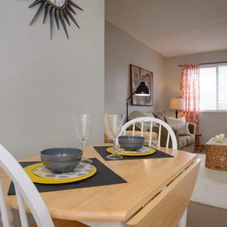 A cozy dining area with a neatly set table, leading into a bright living room.