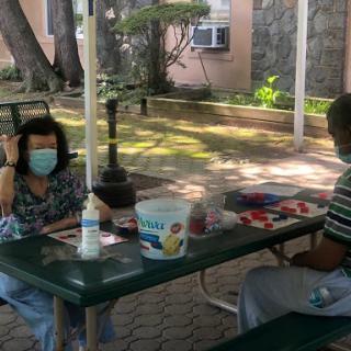 Two individuals enjoying a conversation at a park table, both wearing face masks.