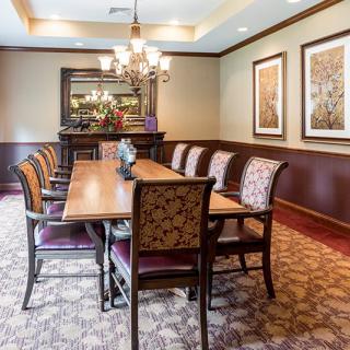 A well-decorated dining room featuring an elegant table with patterned chairs, a chandelier, and framed artwork on the walls.