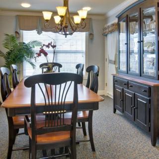 A traditional dining room with a wooden table, chairs, and a large cabinet under a chandelier.