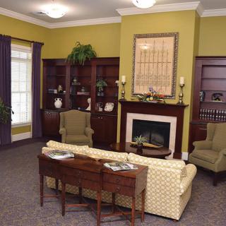 A cozy traditional living room with a fireplace, bookshelves, and comfortable seating.