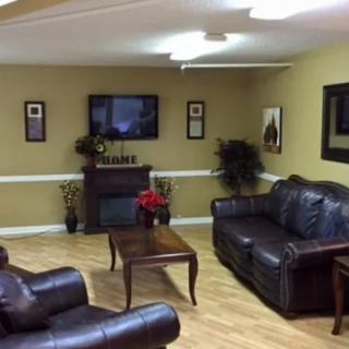 A cozy living room with leather sofas, a coffee table, a mounted TV, and decorative plants.