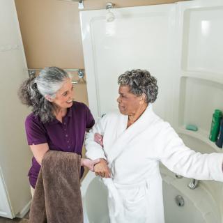 A caregiver assisting an elderly woman in the bathroom.