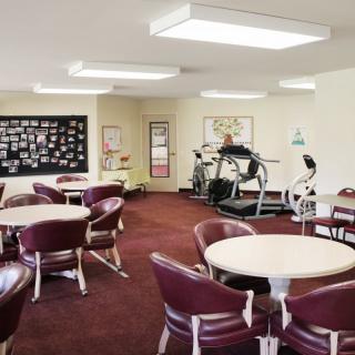A community room featuring tables, chairs, and fitness equipment.