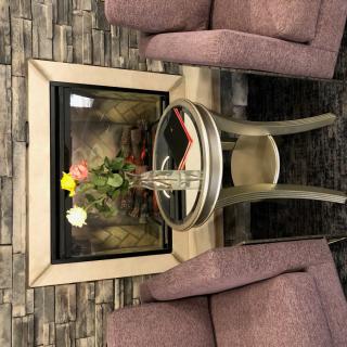 A cozy seating area featuring two chairs by a fireplace, decorated with a small table and a vase of flowers.