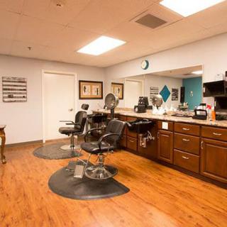 An empty barber shop with wooden floors and styling chairs.