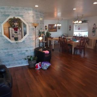 A cozy living and dining area with wooden flooring, adorned with decorative items, plants, and a wall mirror.