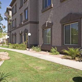 A residential apartment building with a well-maintained lawn and sidewalk.