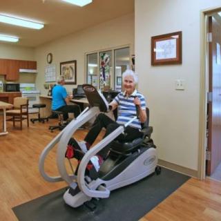 An elderly person exercising on fitness equipment in a rehabilitation center.