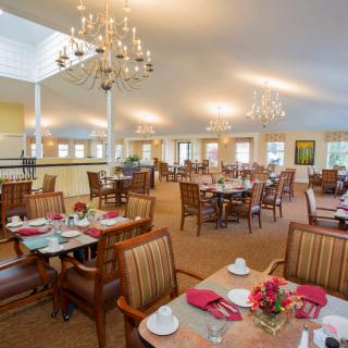 A spacious dining area with elegant chandeliers and neatly arranged tables and chairs.