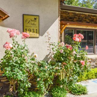 A charming building exterior with blooming roses in a sunny garden, featuring a plaque on the wall.