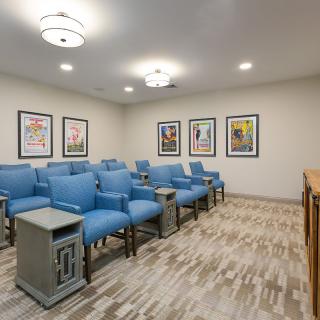 A cozy home theater room with blue chairs and movie posters on the walls.