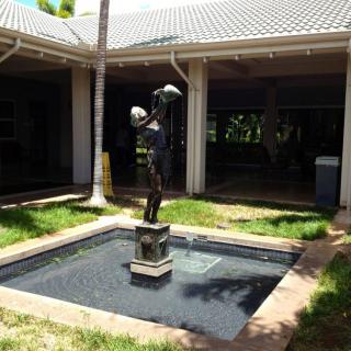 A statue stands in the center of a small fountain located in an outdoor courtyard.