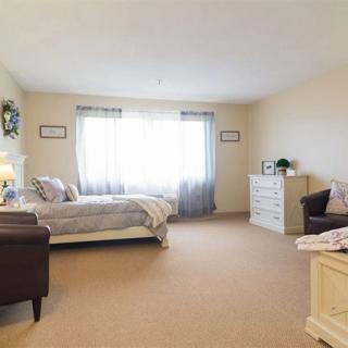 A spacious bedroom with a bed, dresser, and armchair.