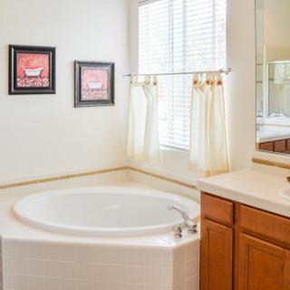 A bright bathroom with a circular bathtub, wooden cabinets, and artwork on the walls.