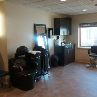 A view of a hair salon interior featuring styling chairs, a mirror, and storage.