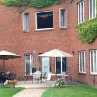 A charming brick building with a cozy patio featuring outdoor furniture and umbrellas, adorned with ivy.