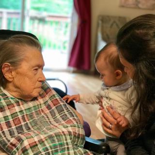 A heartwarming moment between an elderly person, a baby, and another adult indoors.