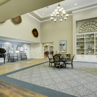Elegant lobby with a central table and chairs, a chandelier overhead, and tasteful decor.