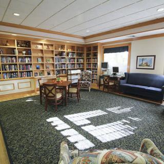 A cozy library with bookshelves, a reading table, and comfortable seating.