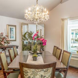 A beautifully decorated dining room with a chandelier and floral centerpiece.