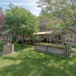 A serene garden with lush greenery and a brick building in the background.