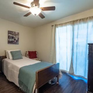 A cozy bedroom with a single bed, ceiling fan, and wooden flooring.