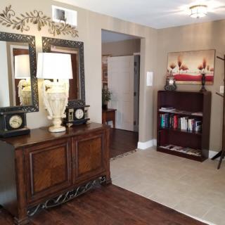 A cozy living room with elegant furniture and decor, featuring a mirror, lamp, and bookshelf.