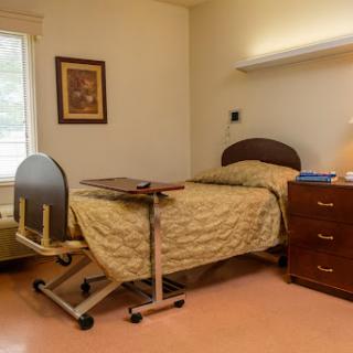 A comfortable hospital patient room with a bed, bedside table, and window.