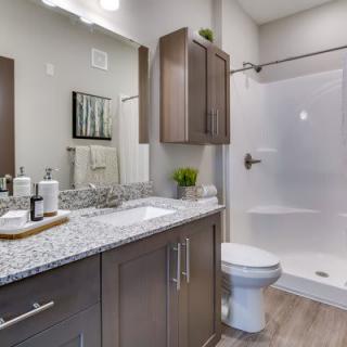 A modern bathroom with a granite countertop, shower enclosure, and sleek cabinetry.