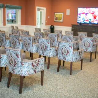 A room set up with rows of patterned chairs facing a television screen.