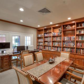 A cozy library office with a conference table and bookshelves filled with books.