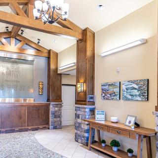 A modern lobby with wood accents and elegant decor, featuring a chandelier and artwork on the walls.