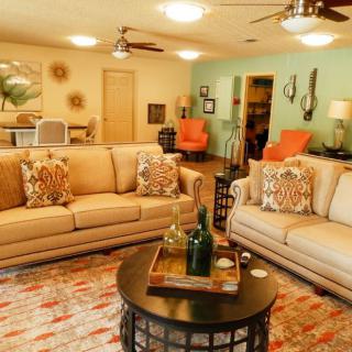 A cozy living room with beige sofas, a round coffee table, decorative pillows, and stylish wall art.