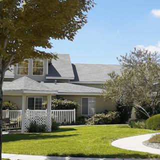 A suburban house with a well-maintained lawn, a gazebo, and surrounding trees.