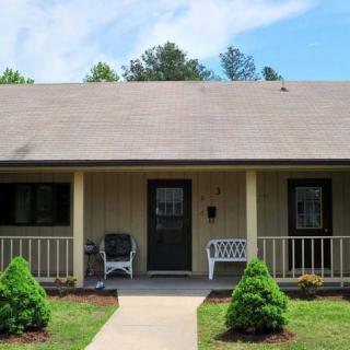 A suburban house with a front porch, surrounded by a neatly maintained yard and trees.