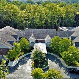 Aerial view of a mansion surrounded by trees with a circular driveway.