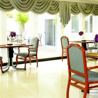 A bright dining area with elegantly arranged tables and chairs, decorated with flowers.