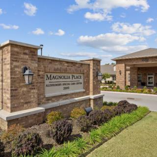 Entrance to Magnolia Place apartment complex with landscaped surroundings.