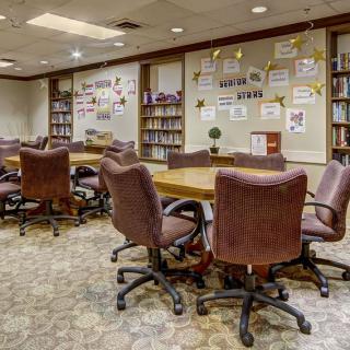 A conference room with bookshelves, tables, and chairs, resembling a library setting.