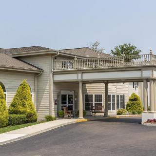 Entrance of a building with a covered driveway and landscaped surroundings.
