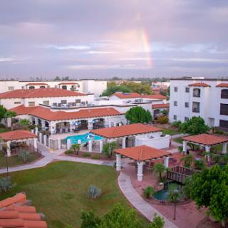 A picturesque view of a resort featuring vibrant gardens and buildings under a rainbow.